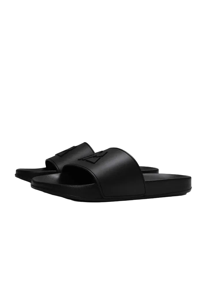 A pair of black slide sandals with a minimalist geometric logo on the strap, shown against a solid light gray background.