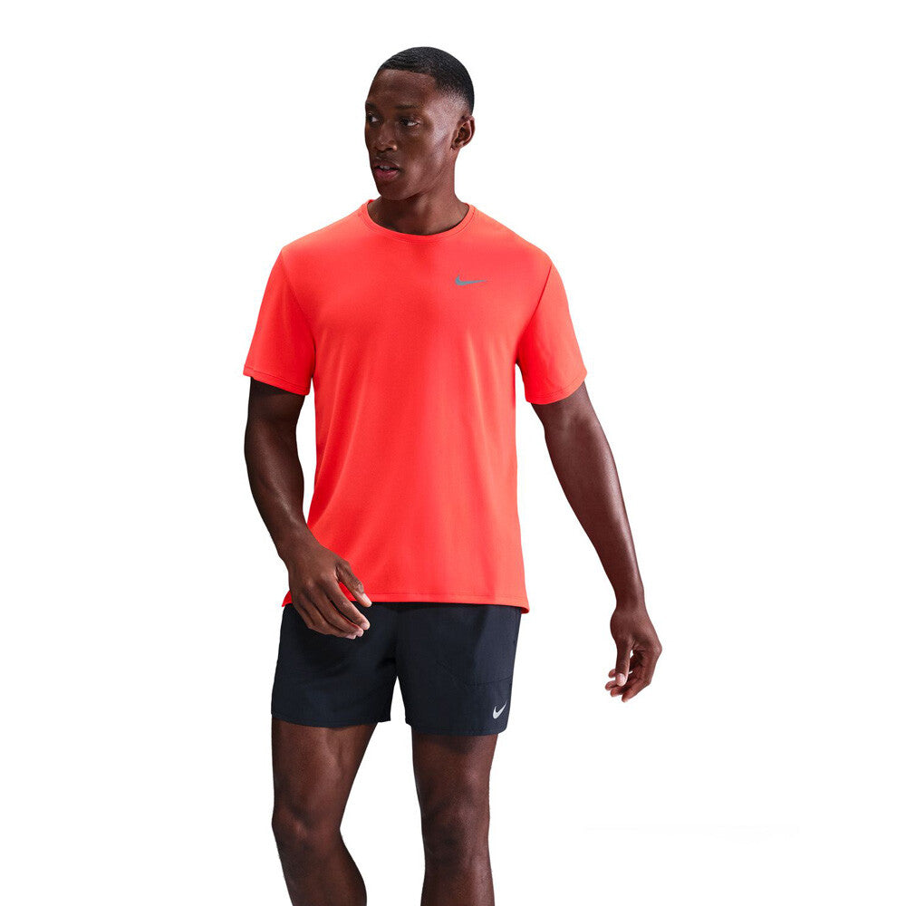 Man wearing a bright orange athletic shirt and black shorts on a white background